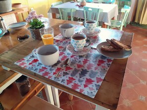 A breakfast table with a coffee cup, a glass of orange juice, a plate of toast, and a spoon.