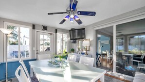 Una cucina moderna con zona pranzo, ventilatore a soffitto e televisore sopra il bancone.