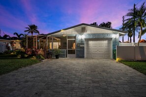 Ein Wohnhaus mit überdachter Veranda, Garage und einem gepflegten Vorgarten.