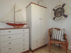 A room with a white wardrobe, a wooden chair with a striped cushion, and a wall decoration with 'WELCOME ON BOARD' text. - Rollies Retreat (Fowey)