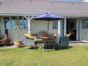 A patio with a table and chairs, a potted plant, and a chimney. - Rollies Retreat (Fowey)