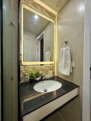 A bathroom with a large mirror, a sink, and a towel rack. - 2 Bedroom - Tropical Suite Apartment by Lux Haven Stays - Central Lahore (Lahore)