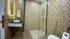 Une salle de bain moderne avec une douche à parois de verre, des toilettes blanches et un lavabo avec un miroir.