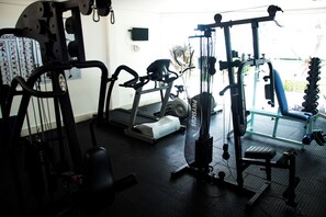 Ein Fitnessraum mit Trainingsgeräten, Laufband und Langhantelbank.