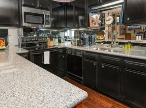 Una cocina moderna con encimeras de granito, electrodomésticos de acero inoxidable y muebles oscuros.