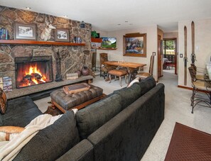 Una sala de estar con chimenea de piedra, un sofá, una mesa de comedor y un televisor.