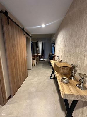 A modern kitchen with a wooden table, a hanging light fixture, and a sliding door. - Confortable Depa 2 BR A/C, Chapu, Gym, Cas y Expo (Guadalajara)