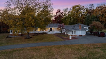 A two-story house with a porch, a driveway, and a lawn.