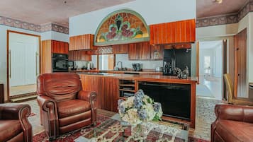 A spacious living room with a fireplace, leather armchairs, and a coffee table with decorative items.