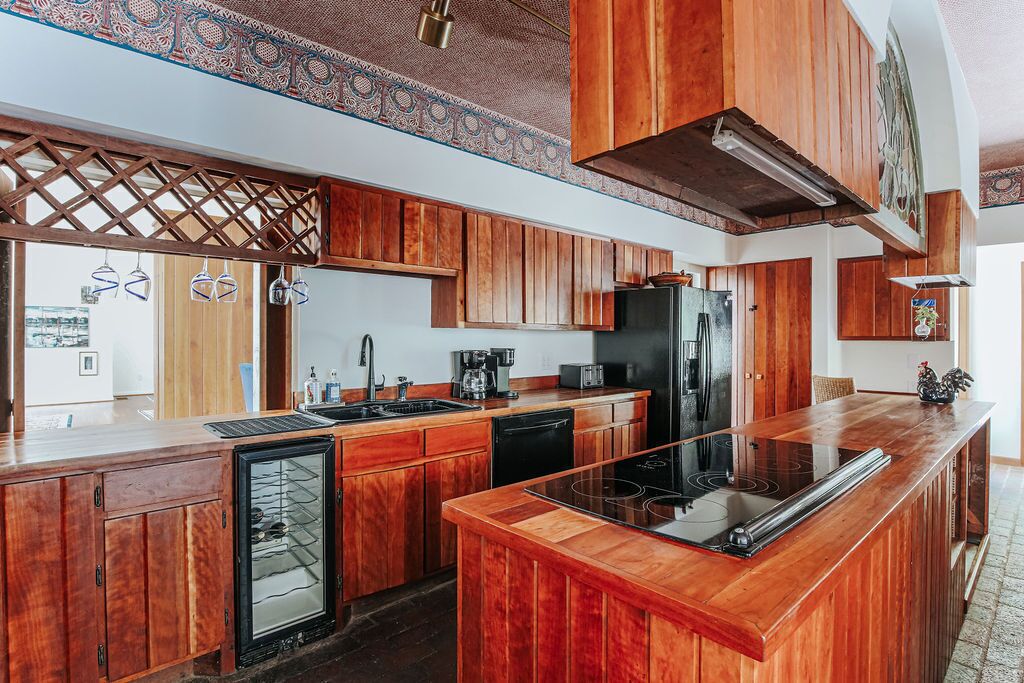 A kitchen with wooden cabinets, a refrigerator, a dishwasher, and a bar area.