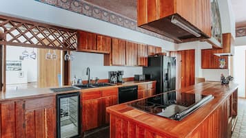A kitchen with wooden cabinets, a refrigerator, a dishwasher, and a bar area.