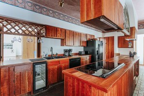 Eine Küche mit Holzausstattung, einem Kühlschrank, einem Geschirrspüler und einer Bar.
