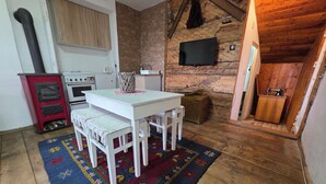 Una cocina acogedora con una mesa blanca, estufa roja y televisor montado en la pared.