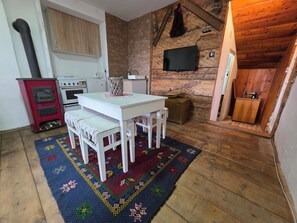 Una cocina acogedora con una mesa blanca, estufa roja y televisor montado en la pared.