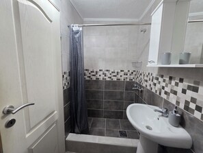 Un baño con ducha, lavabo e inodoro.