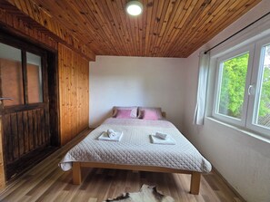 A wooden-paneled room with a bed, a window, and a door. - Apartments Javorje Žabljak - Rustic Peak Family Apartment  (Žabljak)