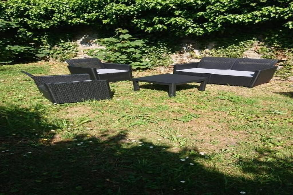 Un área de estar al aire libre con un sofá, dos sillones y una mesita.
