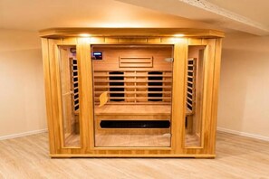 Un sauna en bois, doté d’un panneau de commande, d’un banc et d’une porte en verre.