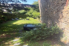 Un mur de pierre, une zone herbeuse avec un petit étang et un banc.