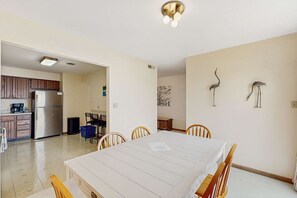 Une cuisine moderne équipée d’un réfrigérateur, d’une cuisinière et d’un four à micro-ondes. Un coin repas avec une table et des chaises est également disponible.