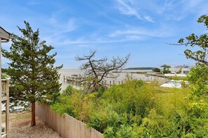 A residential area with a wooden fence, a tree, and a view of a body of water with a dock. - Baystrand II in Dewey Beach walk to beach (Dewey Beach)