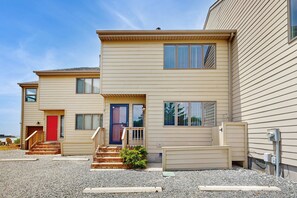 A two-story building with a red door, a staircase leading to the entrance, and a small porch area. - Baystrand II in Dewey Beach walk to beach (Dewey Beach)