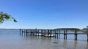 Une jetée s’avançant dans une eau calme, sous un ciel dégagé.