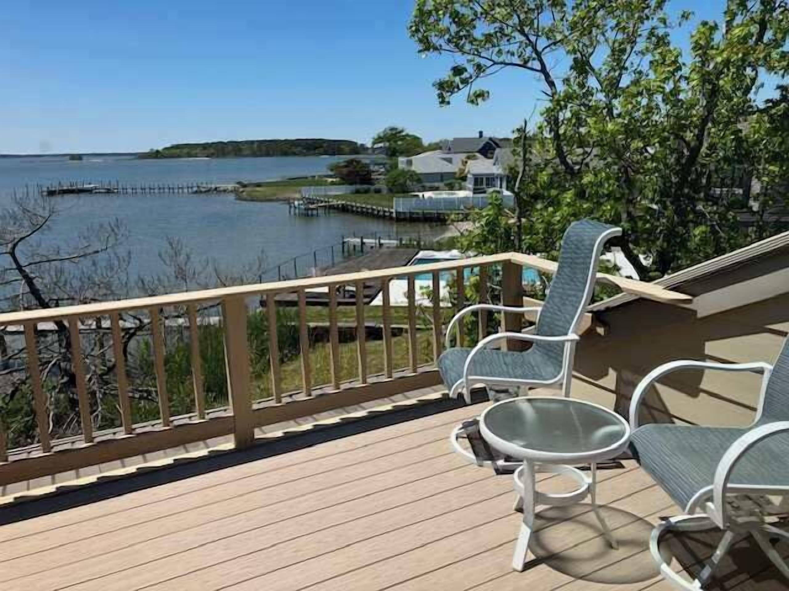 Une terrasse dotée de mobilier d’extérieur, offrant une vue sur un plan d’eau et un quai.