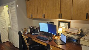 Ein Home-Office mit Schreibtisch, Computer, Drucker und Schränken.