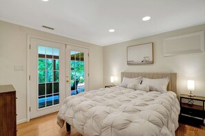 A bedroom with a large bed, a nightstand, a wall-mounted lamp, and a door leading to a balcony. - Mount Vernon Hideaway-45 DAY Minimum Stay (Alexandria)