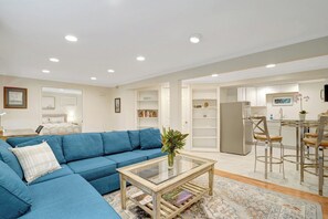 A living room with a blue sofa, a glass coffee table, and a kitchen area with a dining table and chairs. - Mount Vernon Hideaway-45 DAY Minimum Stay (Alexandria)