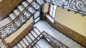 Ein mehrgeschossiges Interieur mit einer Treppe, die kunstvolle schwarze Metallgeländer und Marmorstufen aufweist.