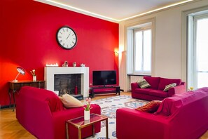 Ein Wohnzimmer mit roten Wänden, einem Kamin, einem Fernseher und zwei roten Sofas.