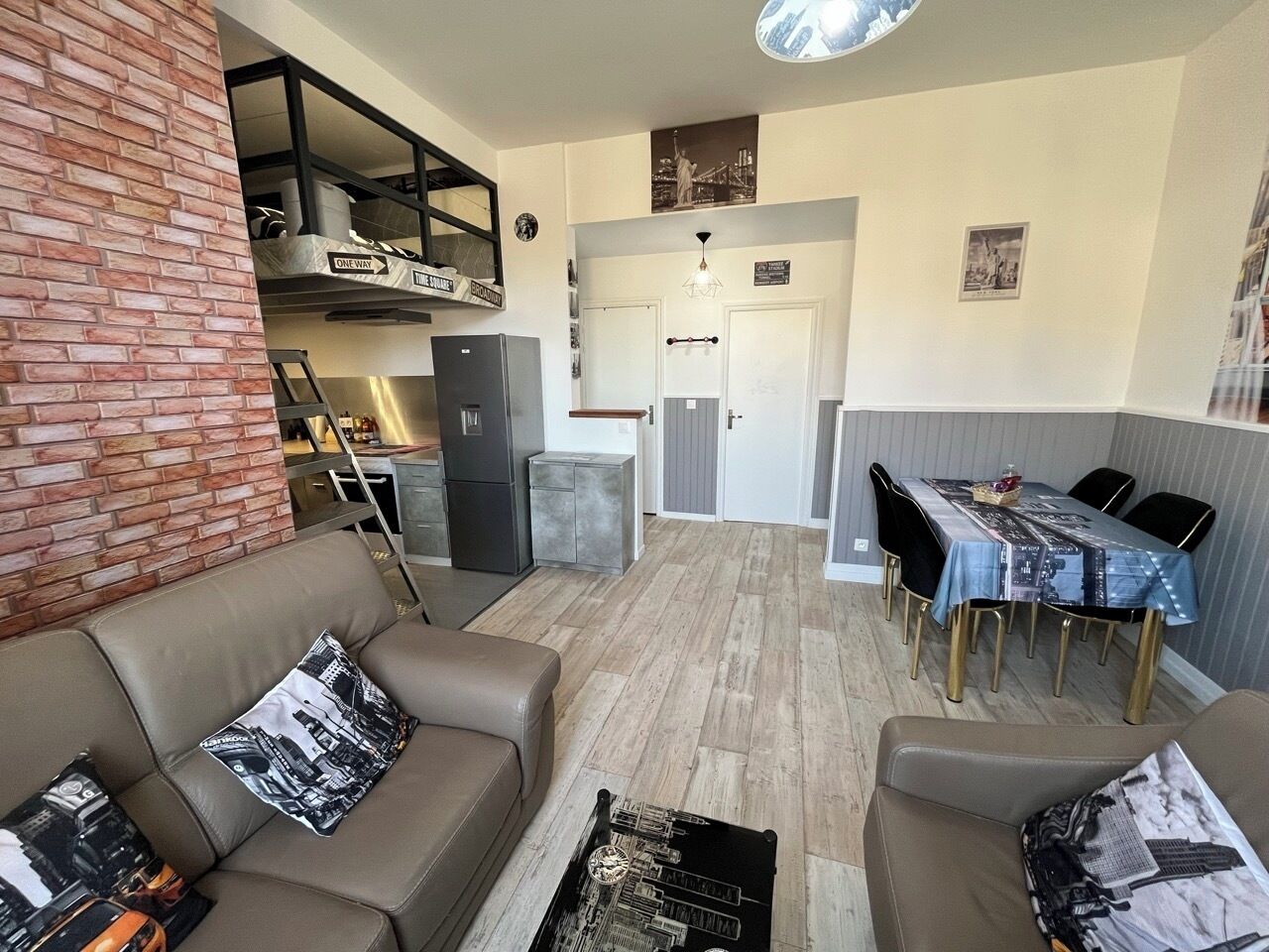 A compact living space with a dining area, kitchenette, and a loft bedroom with a view.