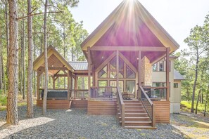 Eine Hütte mit einer großen Veranda, zahlreichen Fenstern und einem Kamin aus Stein.