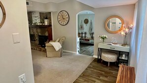 A living room with a fireplace, a clock, a mirror, and a small table with a vase. - The Sanctuary in Warm Springs GA (Warm Springs)