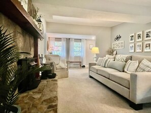 Una sala de estar con un sofá, sillones, una lámpara y una chimenea.