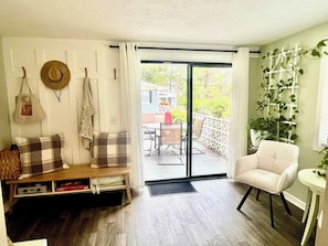 Una habitación con sofá, una silla, una mesa, un banco y vistas al exterior.