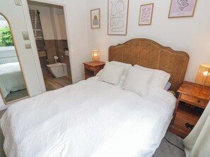 A neatly made bed with white linens, a wicker headboard, and bedside tables with lamps. - 6 Chapel Rock Close (Perranporth)