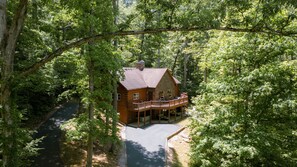 A log cabin with a balcony, surrounded by dense forest. - Big Rock | Theater Room, Hot Tub, Hocking Hills (Rockbridge)