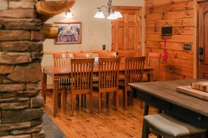 Uma sala de jantar com mesa e cadeiras de madeira, parede de pedra e porta de madeira.
