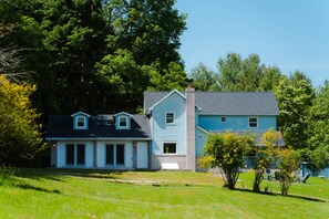 A two-story house with a front porch and a garage. - Whispering Acres | Hocking Hills, Hot Tub, Firepit (Logan)