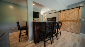 Een moderne keuken met een houten bar, een flatscreen televisie en een schuifdeur in boerderijstijl.