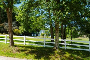 A white fence, trees, and a house in the background. - Whispering Acres | Hocking Hills, Hot Tub, Firepit (Logan)