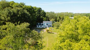 Une maison à deux étages entourée d’une forêt dense.