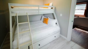 Een stapelbed met een ladder, een enkel bed beneden en een raam met uitzicht.