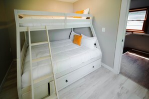 A bunk bed with a ladder, a single bed below, and a window with a view. - Whispering Acres | Hocking Hills, Hot Tub, Firepit (Logan)