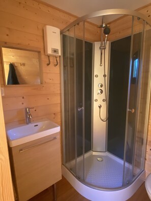 A corner shower with a glass enclosure, a sink, and a mirror. - Tiny Home 'D'Artagnan De La Pausa Verda' with Shared Terrace, Private Garden and Wi-Fi (Montréal)