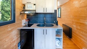 Eine kleine Küche mit Holzwänden, einer Mikrowelle, einem Spülbecken und einem Geschirrspüler.