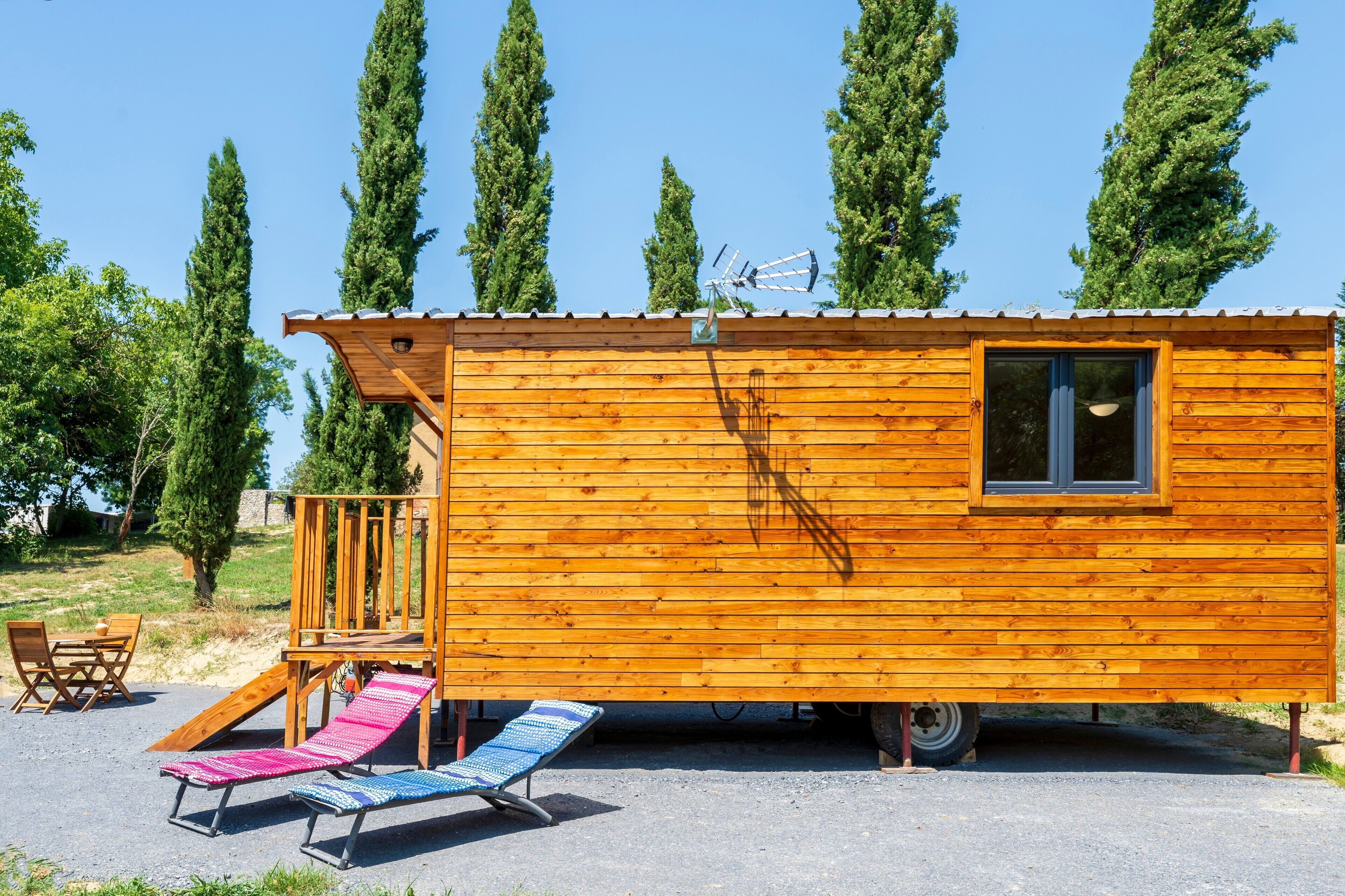 Een houten hut met een raam, een klein terras en een glijbaan.
